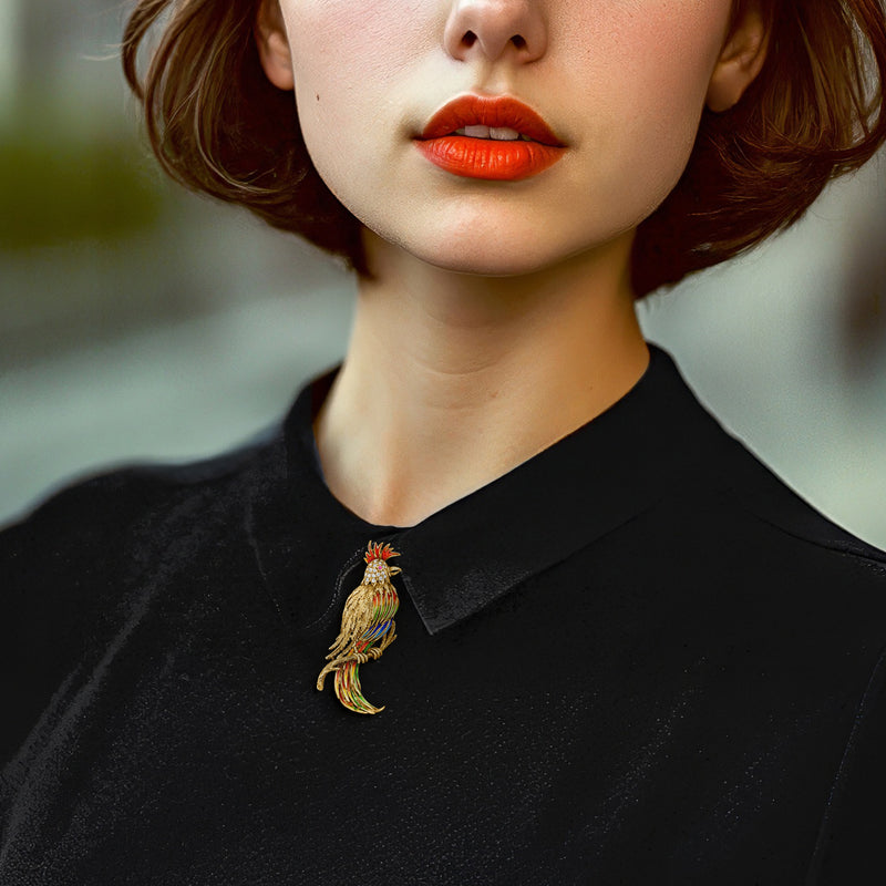Bird pin worn on a black top: yellow gold with multicolor enamel and ruby with clear stones