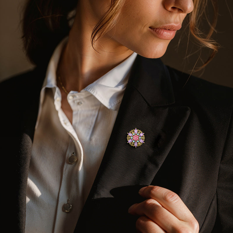Multi-gemstone flower pin with purple, pink, and blue stones on a gold-tone lapel