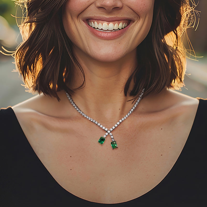 Sterling silver CZ necklace featuring X-shaped pendant with two green simulated emerald stones