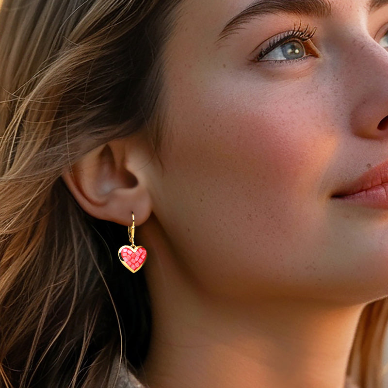 Gold heart drop earrings with pink resin inlay worn on ear, leverback closure