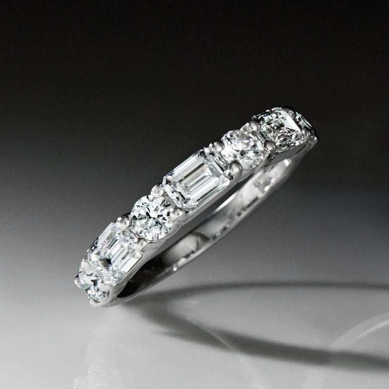 Side view of 14kt white gold ring with emerald-cut center and halo round stones