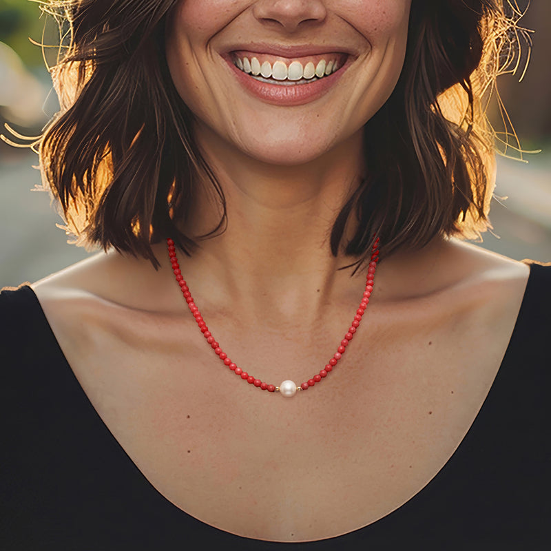 Red coral bead necklace with white pearl centerpiece, worn at neckline