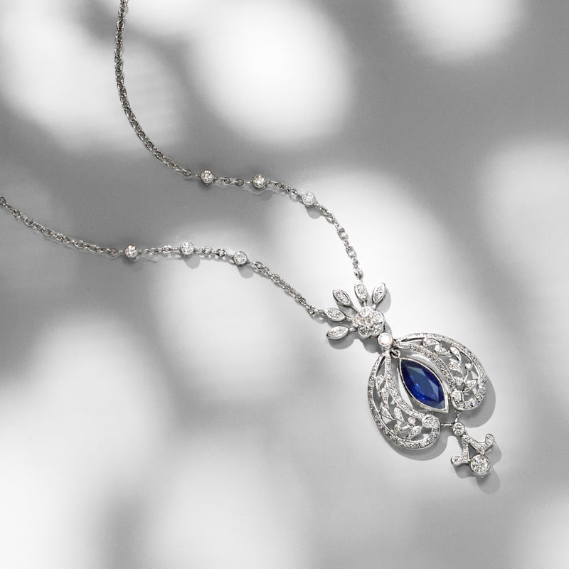 White gold drop necklace with oval blue sapphire pendant and floral diamond accents