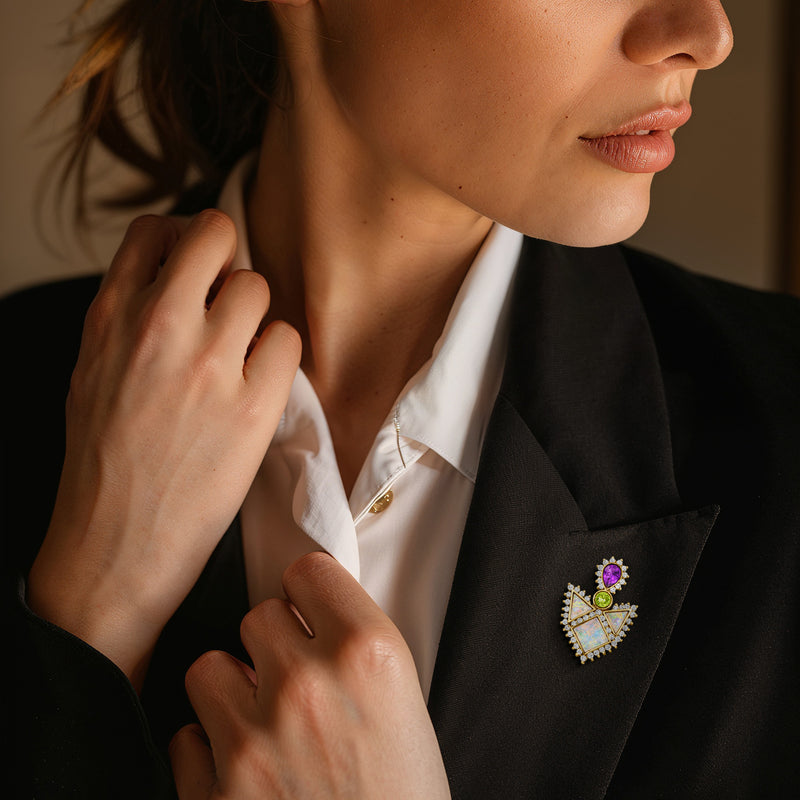 Multicolor geometric gemstone pin on lapel with purple, green, opal, and diamond details