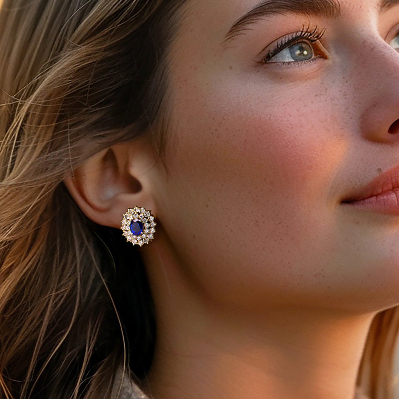 Sapphire & diamond cluster stud earrings with oval blue center, worn on ear