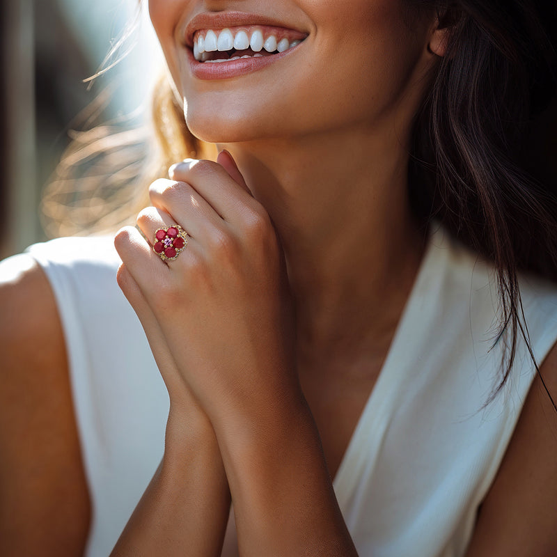 Gold flower ring on hand featuring ruby-red and pink center stones with white accents