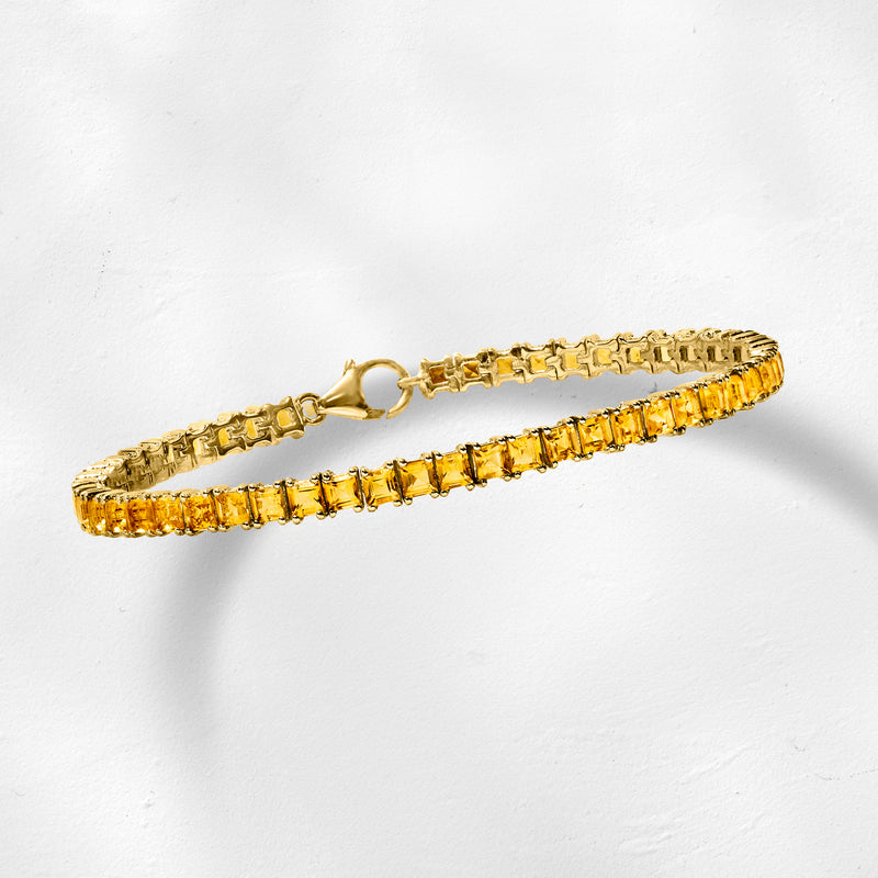 Gold-tone square-stone tennis bracelet with hinged clasp, lying flat