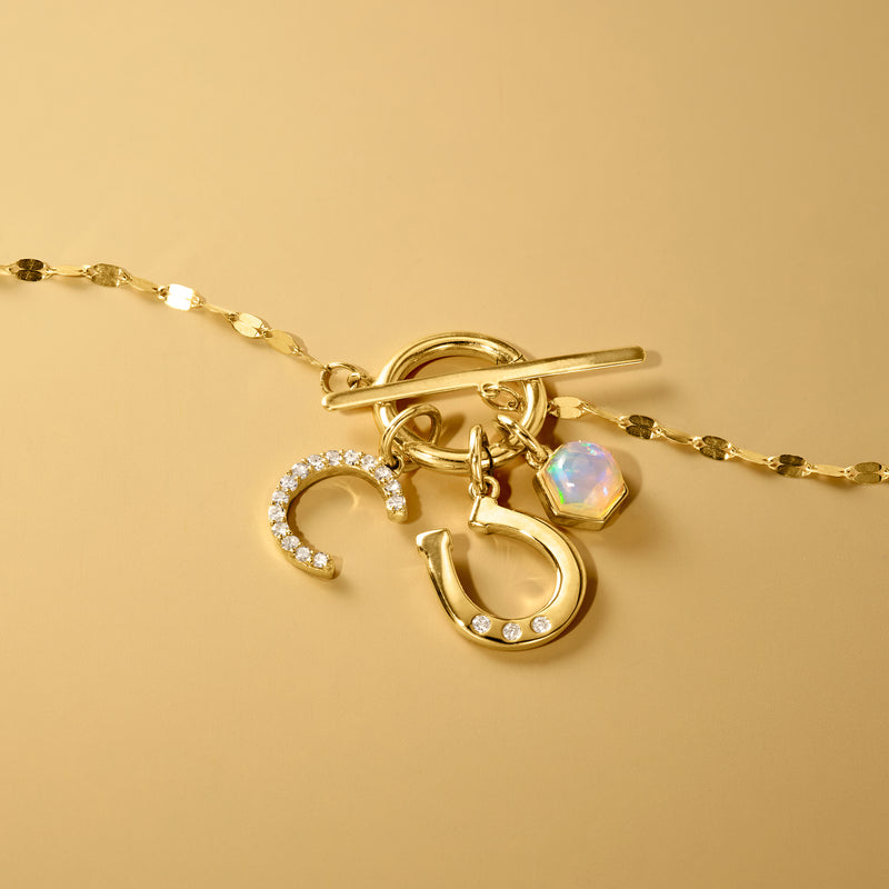 Close-up of yellow gold horseshoe charm with diamond row and matching link chain