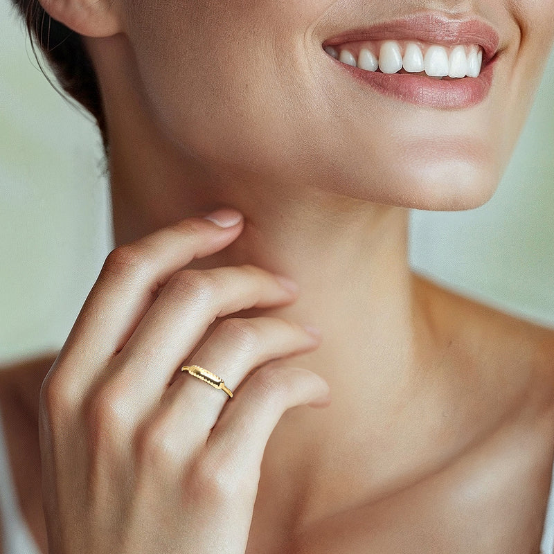 Yellow gold diamond-cut bar ring on finger, faceted oval top