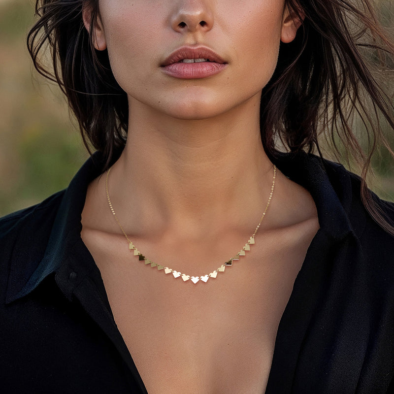 Yellow gold heart station necklace worn with small heart stations at the neckline