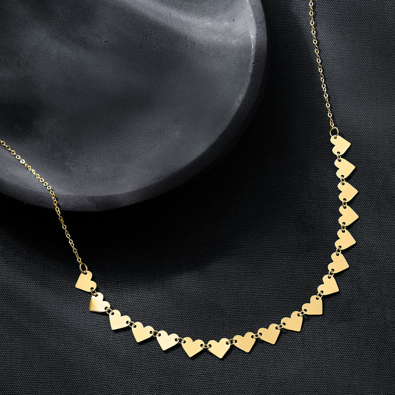 Close-up of yellow gold heart station necklace with linked heart charms on chain