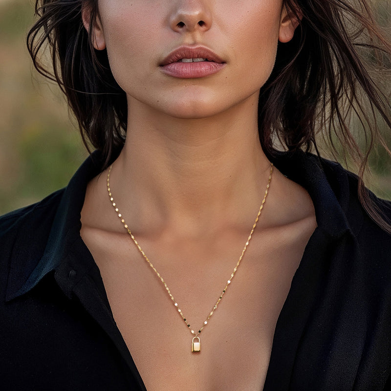 Gold lock pendant necklace on a bead-link chain, worn at the neckline