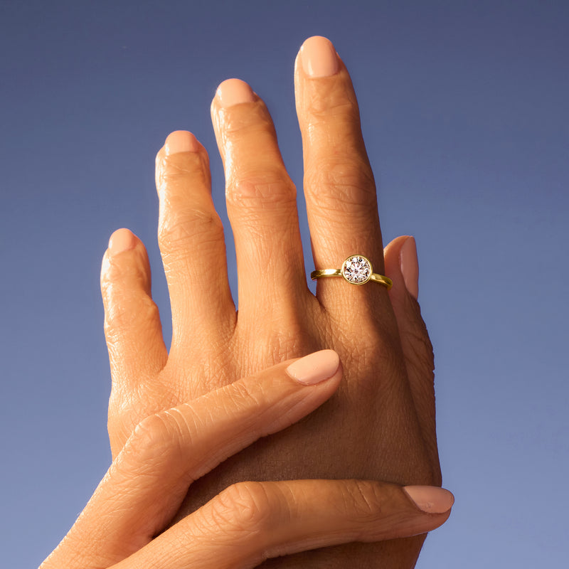 14kt yellow gold solitaire ring with round bezel-set diamond on hand
