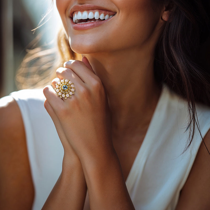 Person wearing gold ring featuring blue topaz, white zircons, and cultured pearls