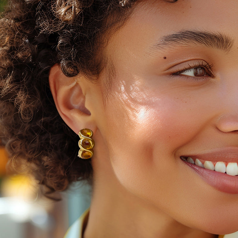 Twisted yellow gold citrine earrings on ear, three amber cabochons