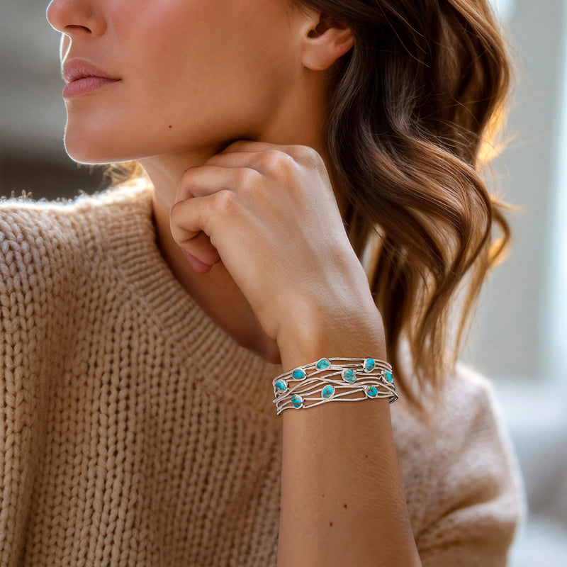 Turquoise stone sterling silver cuff bracelet worn on wrist, oval cabochons in lattice