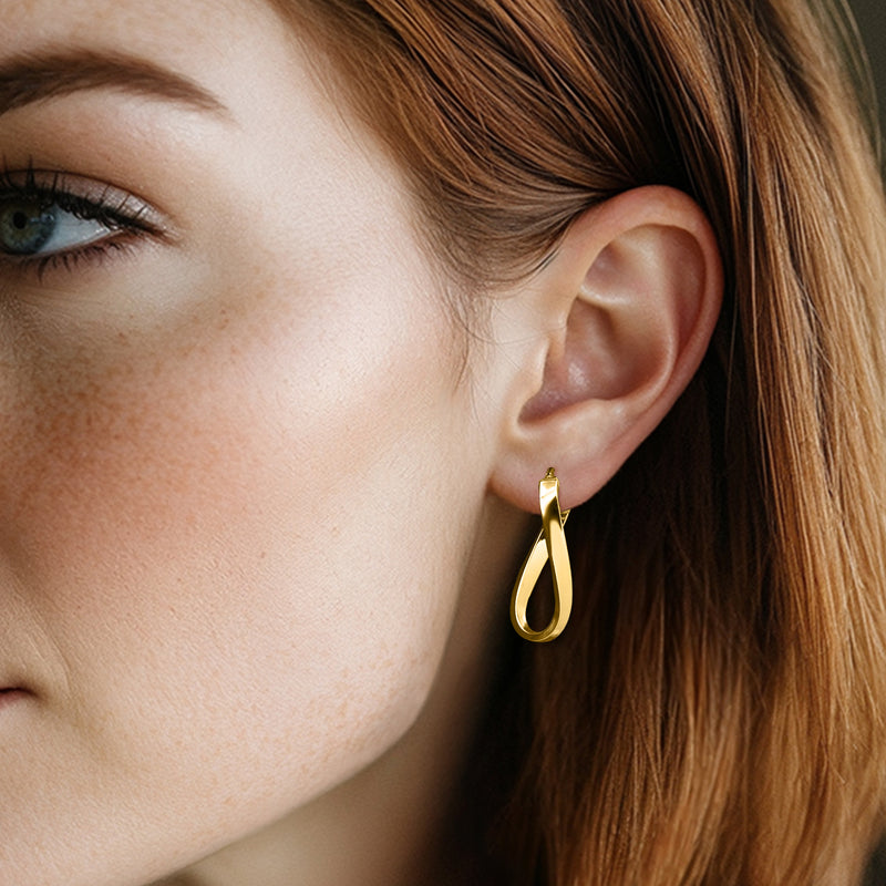 Yellow gold twisted hoop earrings on model ear, small hinged hoop with twisted front.