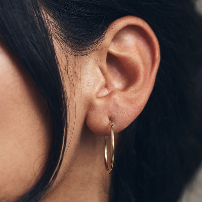10k yellow gold hoop earrings worn on ear, thin polished round hoops