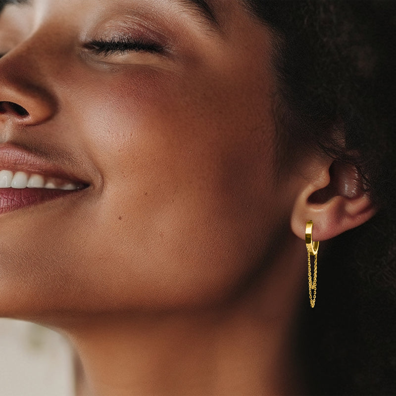 Yellow gold hoop drop earrings with dangling cable-chain on ear