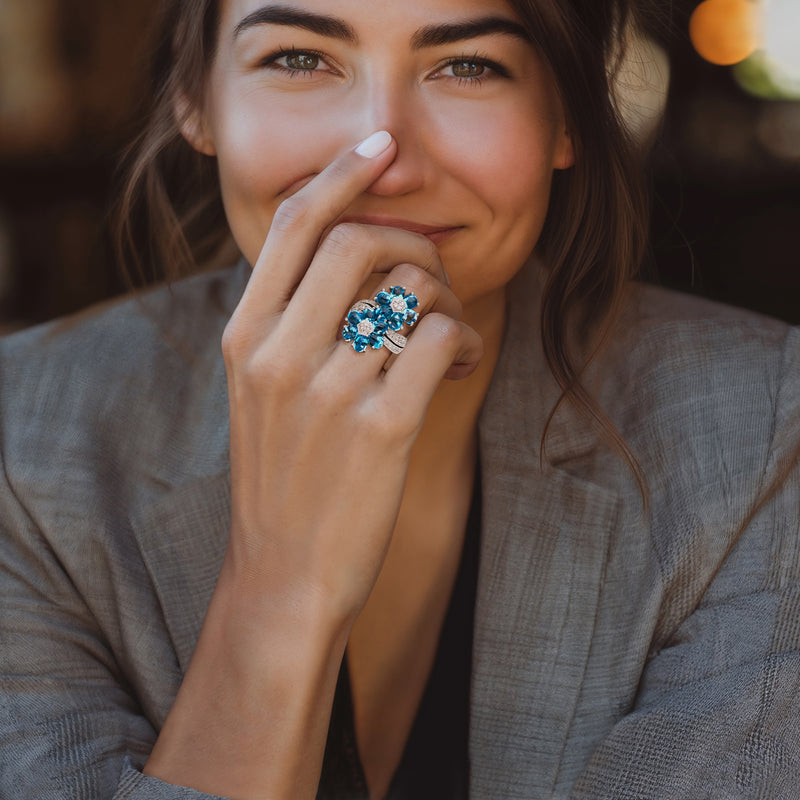 Blue topaz flower ring with diamond clusters on a hand