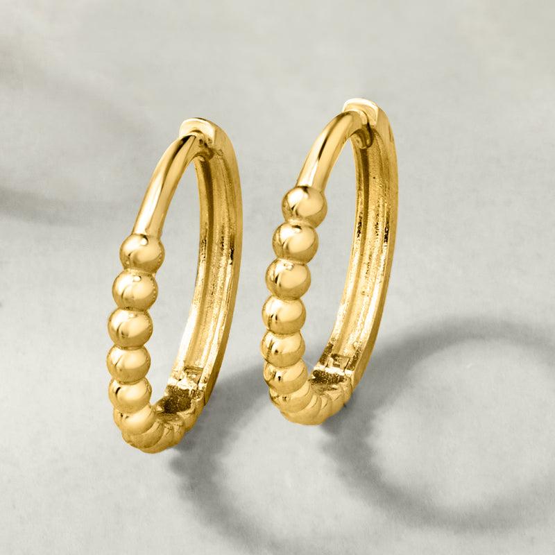 Yellow gold huggie hoop earrings with rounded bead texture along the hoops