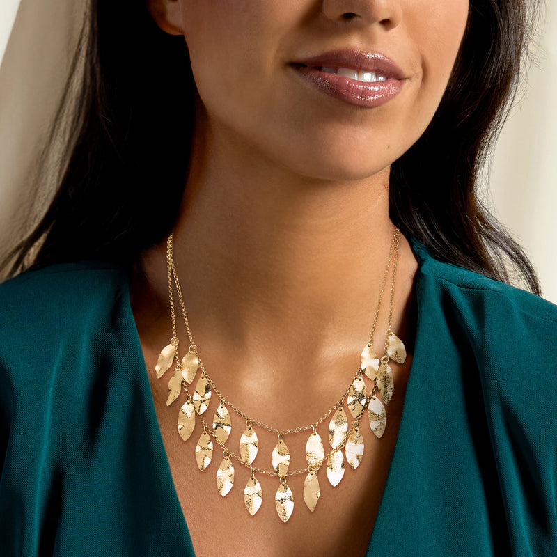 Gold leaf bib necklace with dangling teardrop leaves, worn on neckline