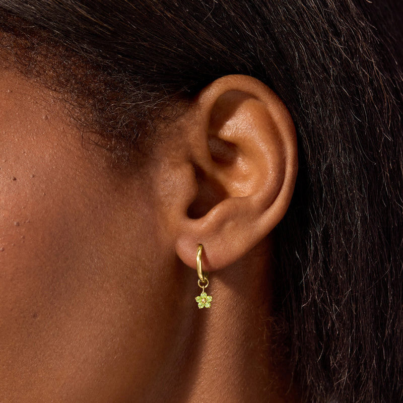 Close-up of 14kt yellow gold peridot flower hoop charm on ear