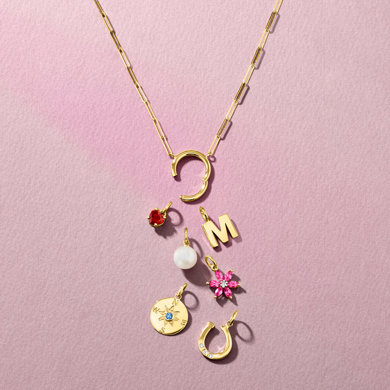 Yellow gold round compass charm with blue star gemstone among other charms