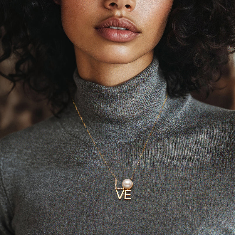Gold pendant necklace worn at collar with round pearl drop and LOVE charm