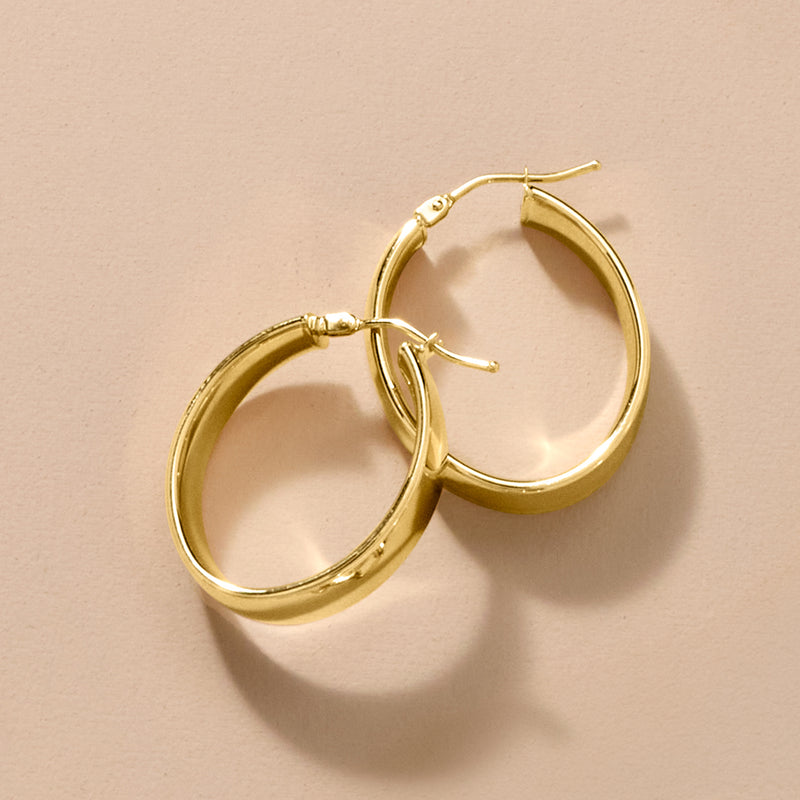Oval 14kt yellow gold hoop earrings, pair shown at slight angle