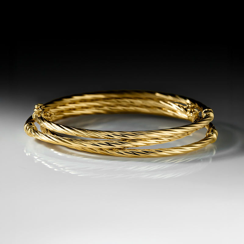 Three twisted 14kt yellow gold bangle bracelets with clasp detail