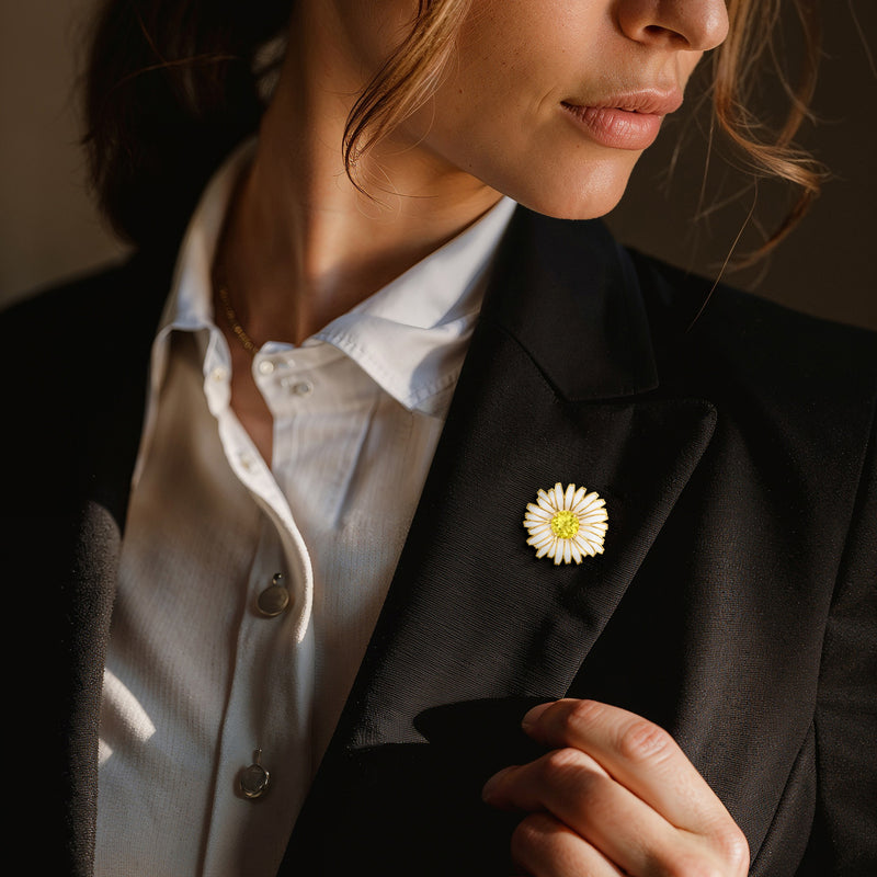Daisy pin/pendant with gold finish, yellow center and white enamel petals on black blazer lapel