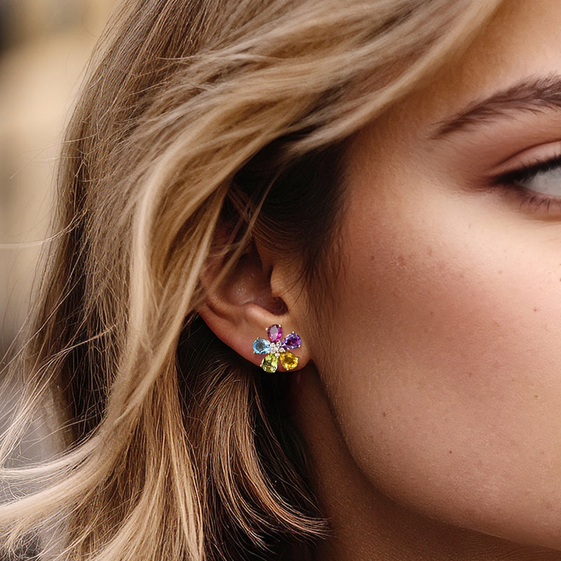 Multi-gem flower stud earrings on ear with purple, green, pink, blue stones and diamonds