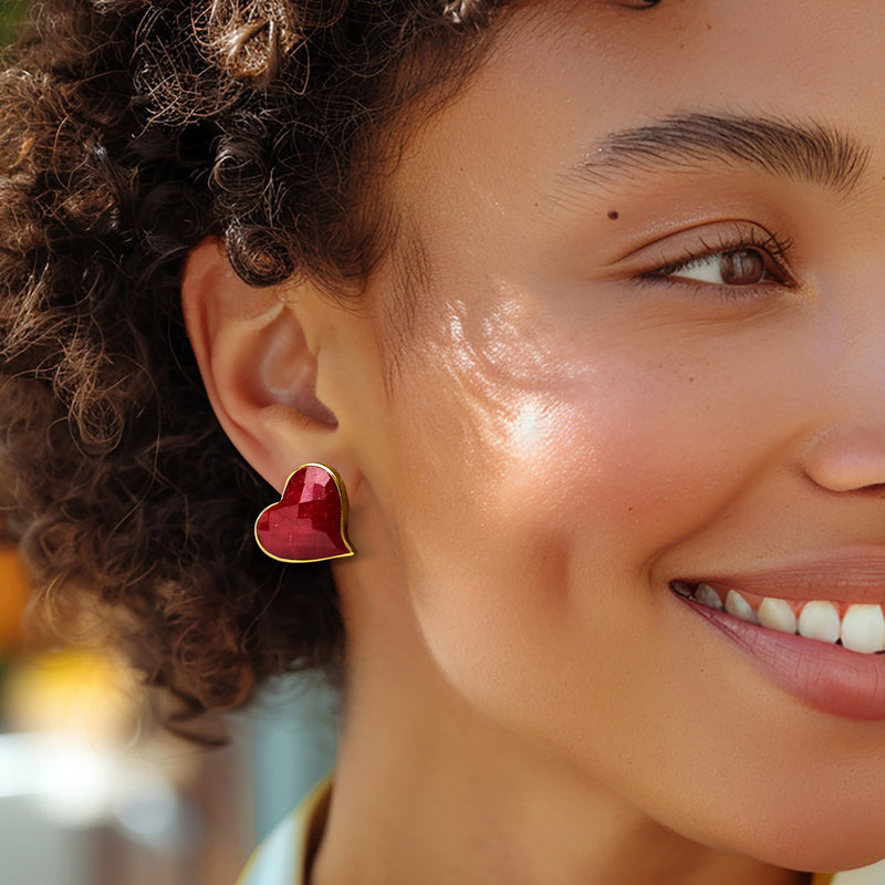 Ruby heart stud earrings with gold border, worn on ear