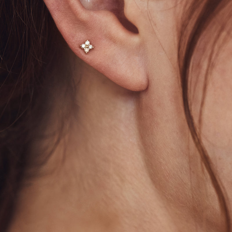 Close-up of yellow gold clover diamond stud earrings on earlobe