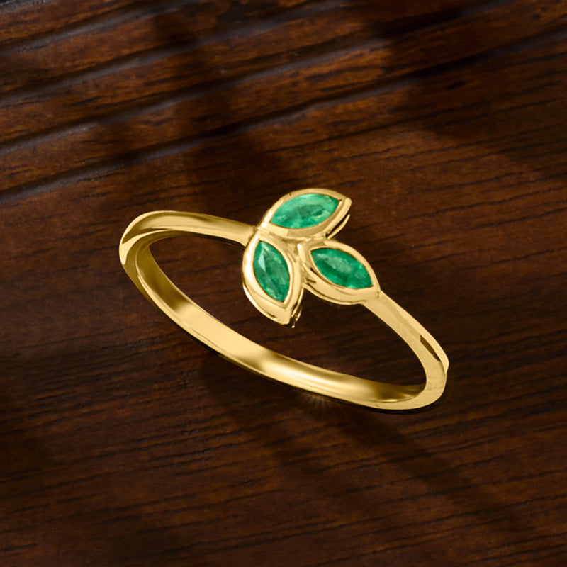 10kt yellow gold emerald leaf ring on wood with three green gemstone leaves