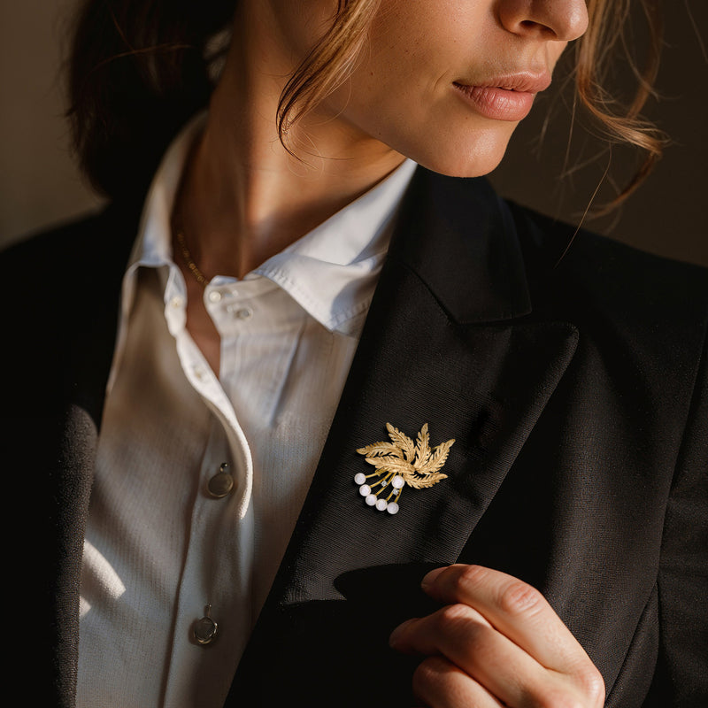 Gold leaf pearl lapel pin on a dark blazer