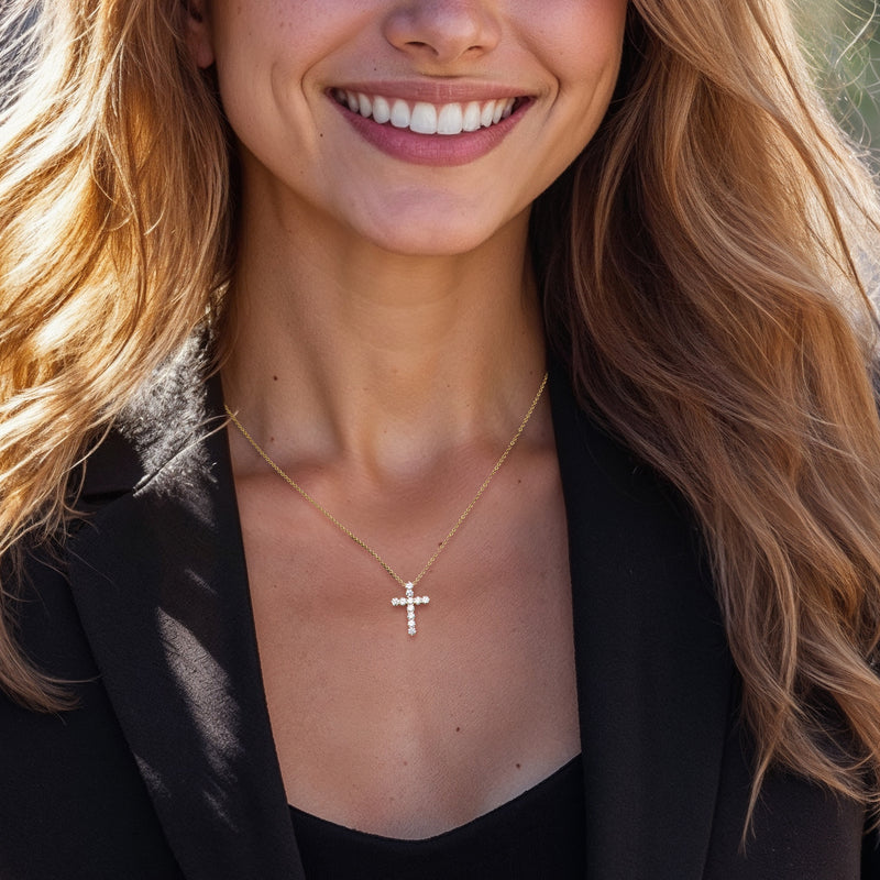 Yellow gold diamond cross pendant necklace worn on a thin chain.