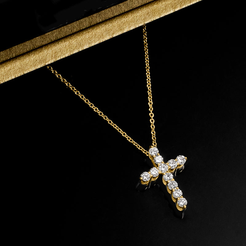 Yellow gold diamond cross pendant on a chain, angled close-up.