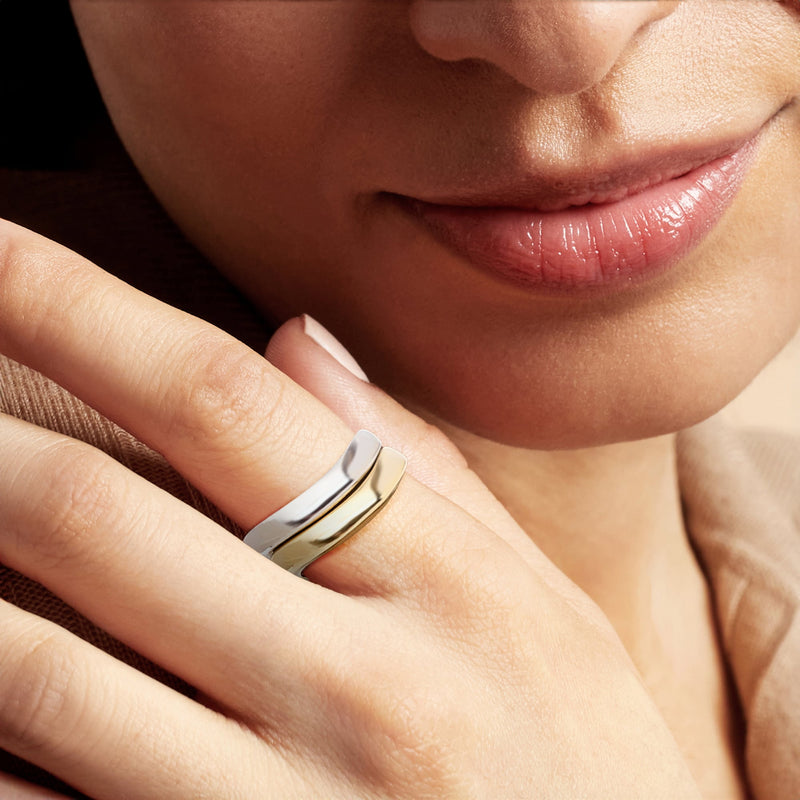 Two wavy rings on finger, gold and silver polished bands with curved tops