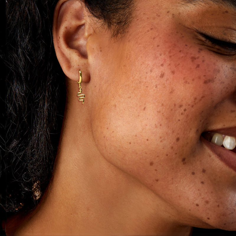 Gold vermeil snake drop hoop earrings worn on model’s ear