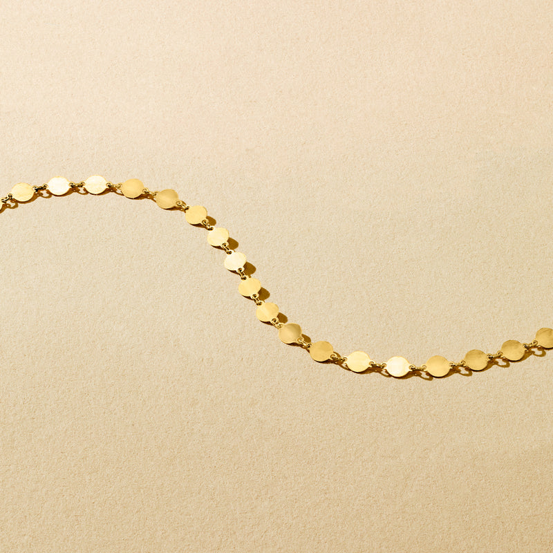 Gold mirror-link necklace detail with oval coin-like links