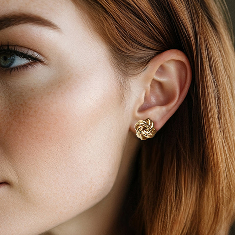 Gold-tone interlocking love knot stud earrings on ear with post backing