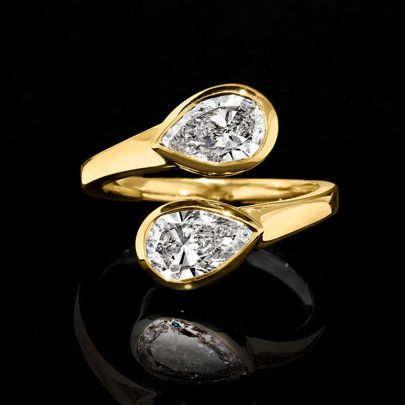 Angle view yellow gold bypass ring with two pear-shaped lab-grown diamonds, bezel-set