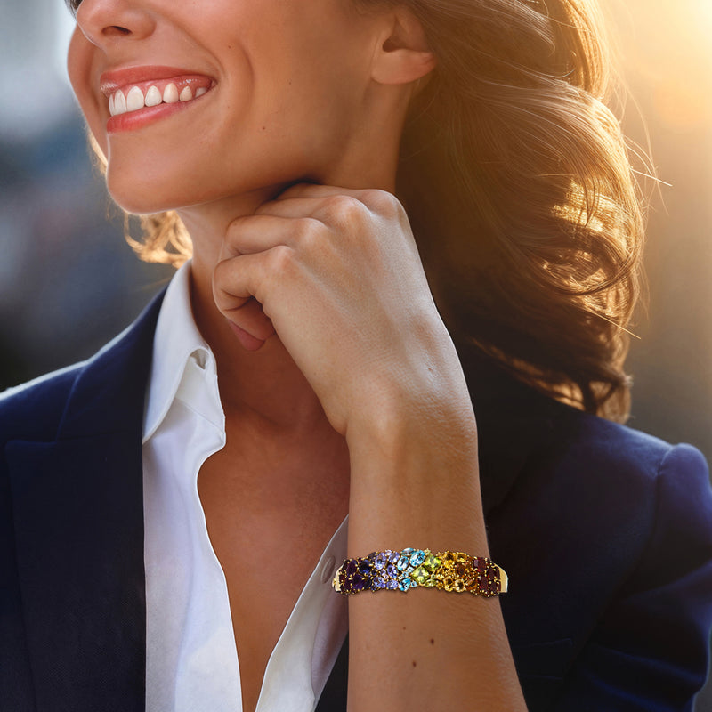 Gold-tone multi-gem bracelet on wrist with rainbow stones and curved bangle