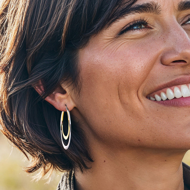 Double hoop earrings on ear, silver outer hoop with gold inner hoop