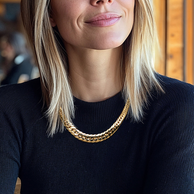 Gold-tone graduated Cuban-link necklace worn at the neckline, braided link detail