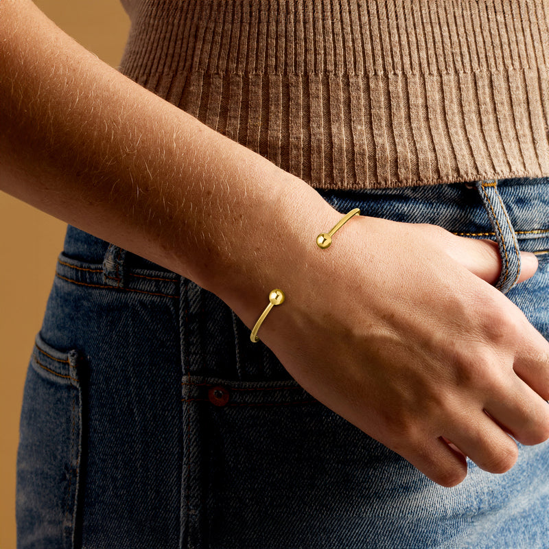 Gold bead cuff bracelet on wrist with two round bead accents
