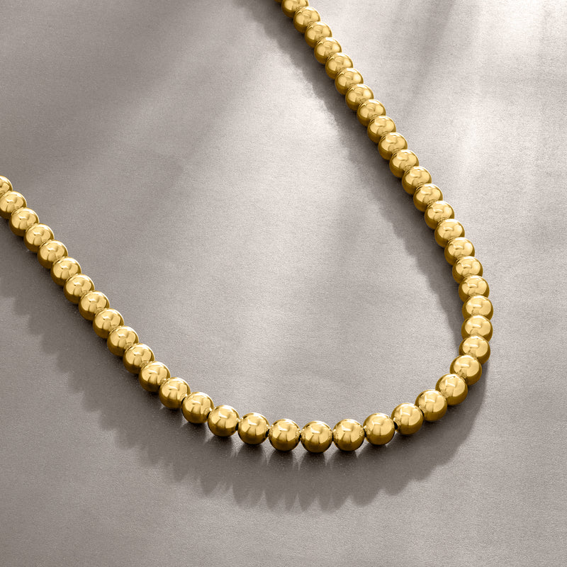 Gold bead necklace close-up showing small round bead chain links.