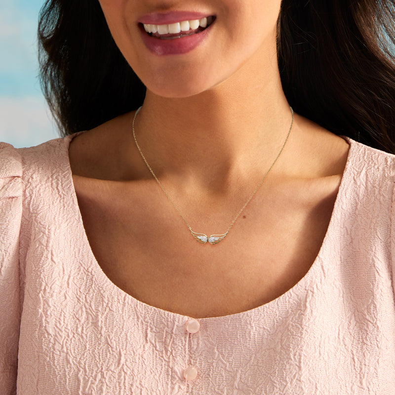 Gold angel wings pendant necklace with two small center stones, worn on the chest